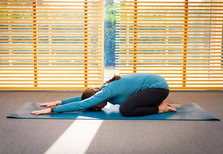 person on yoga mat in child's pose