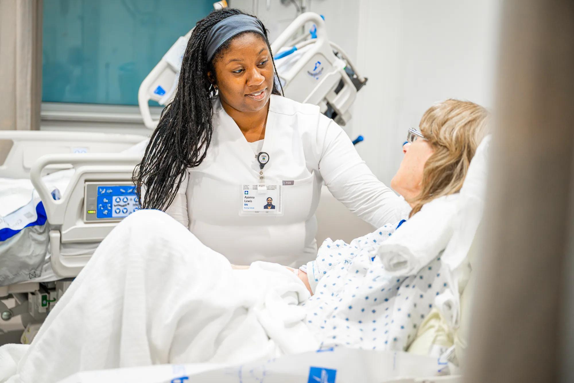 A Cleveland Clinic caregiver speaking with a patient in a hospital bed.