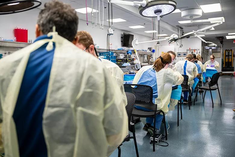 Students sit at tables to practice surgical techniques