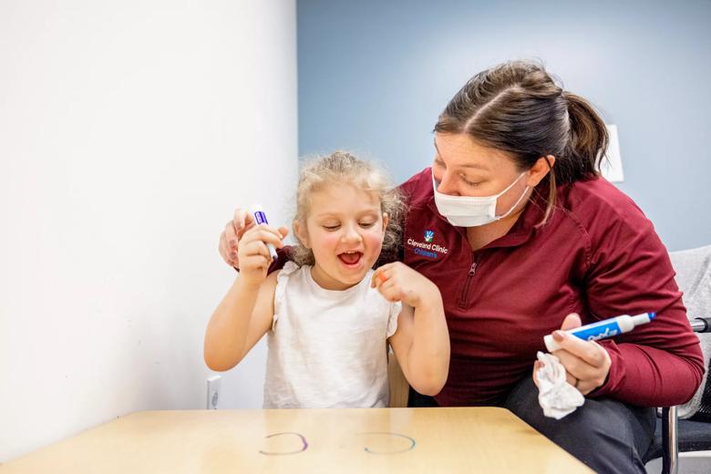 A child and caregiver celebrate after the child draws a shape with a marker