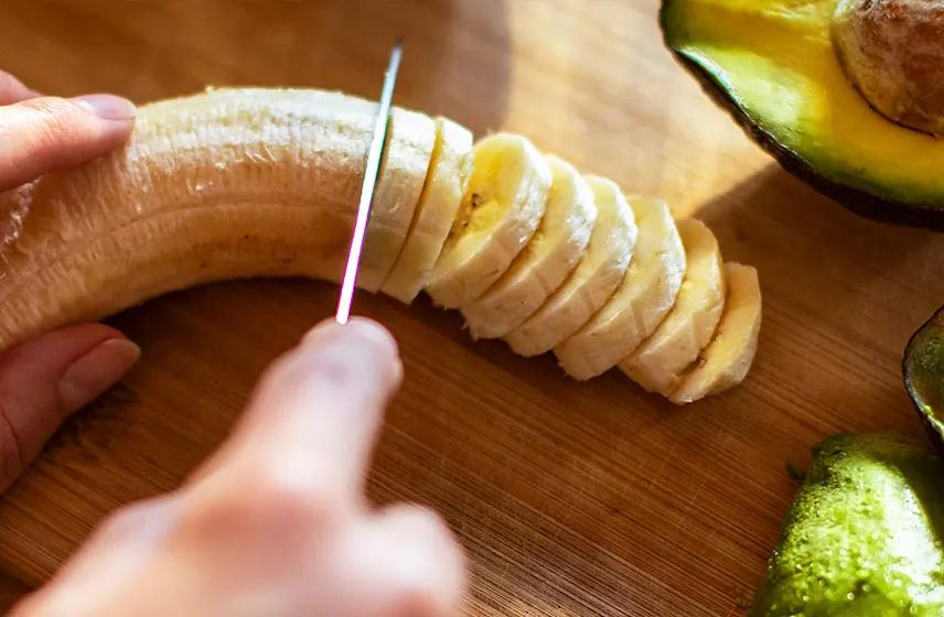 Person dicing up banana and avocados.