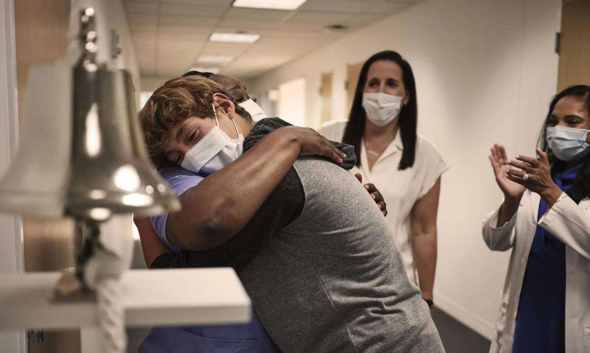 A patient hugging a caregiver after ringing the bell for their last chemotherapy session.