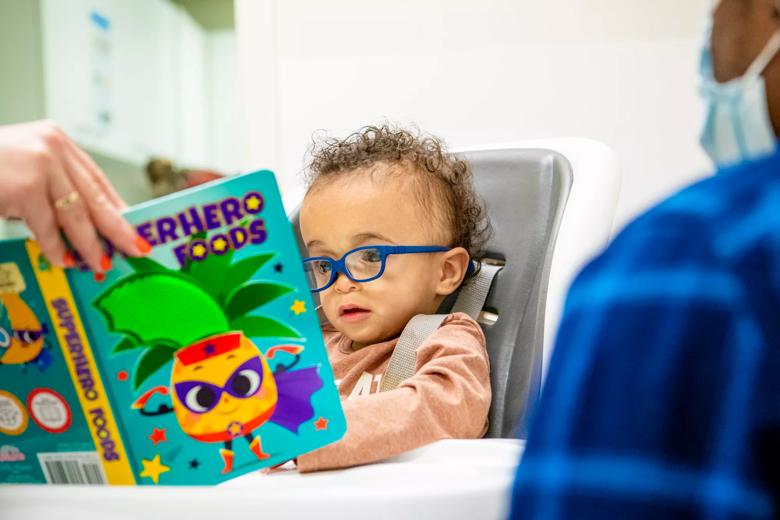 Little boy with blue glasses looks at a picture book
