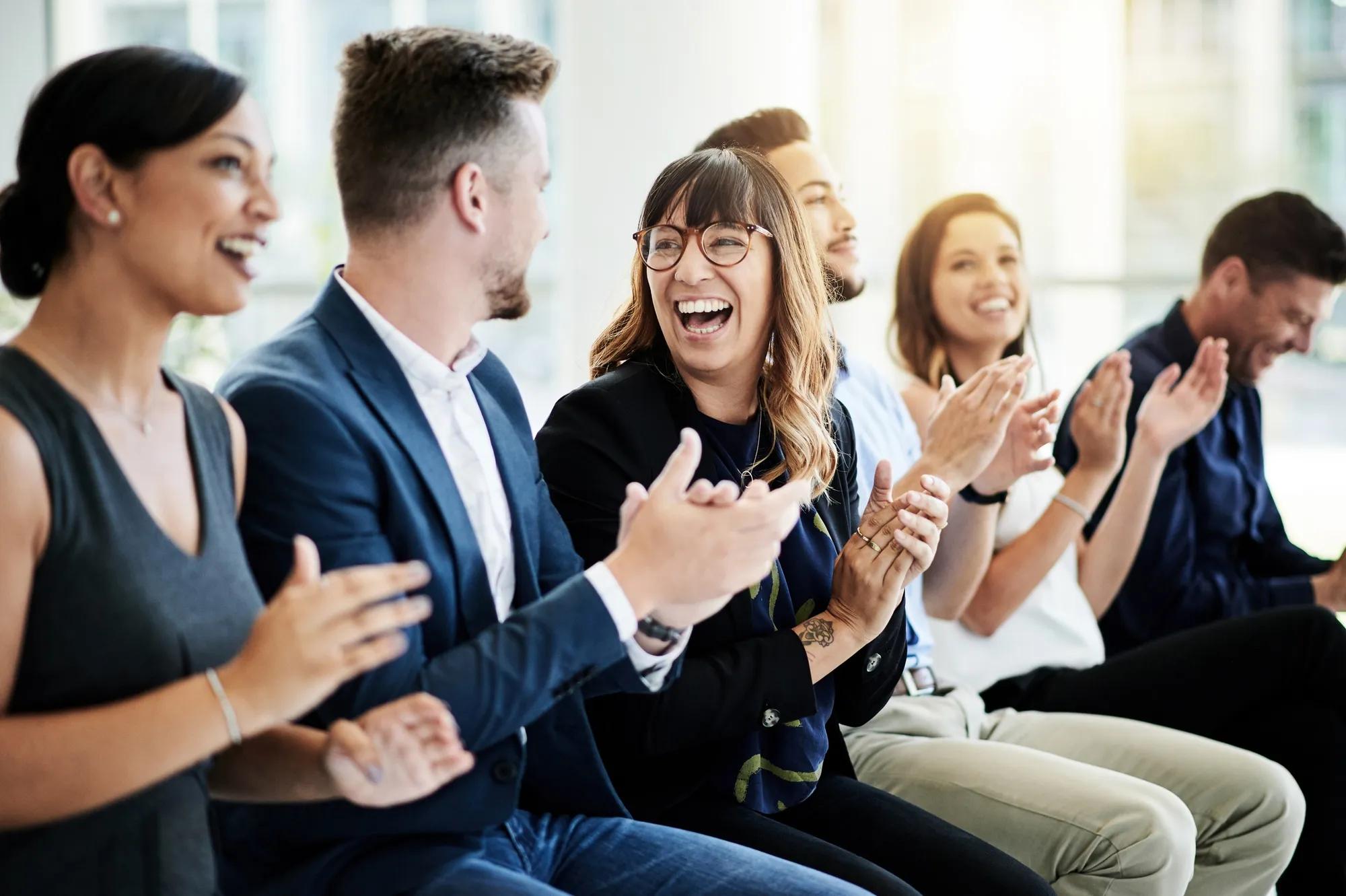 Group of business professionals applauding during a meeting or presentation.