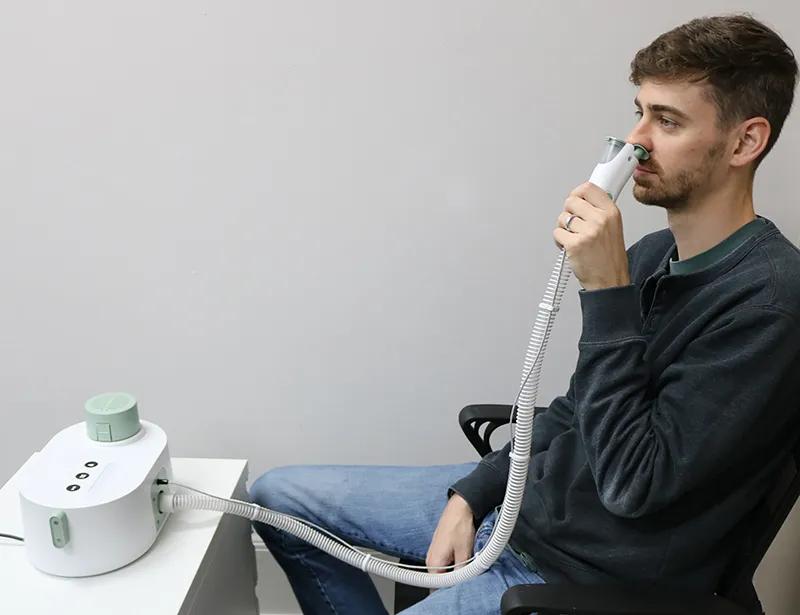 Man demonstrating use of transnasally delivered cool air device