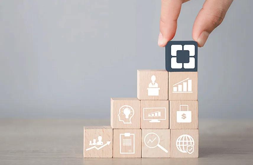 Hand placing a Cleveland Clinic logo on stacked wooden blocks displaying business, growth, analytics, and security symbols.