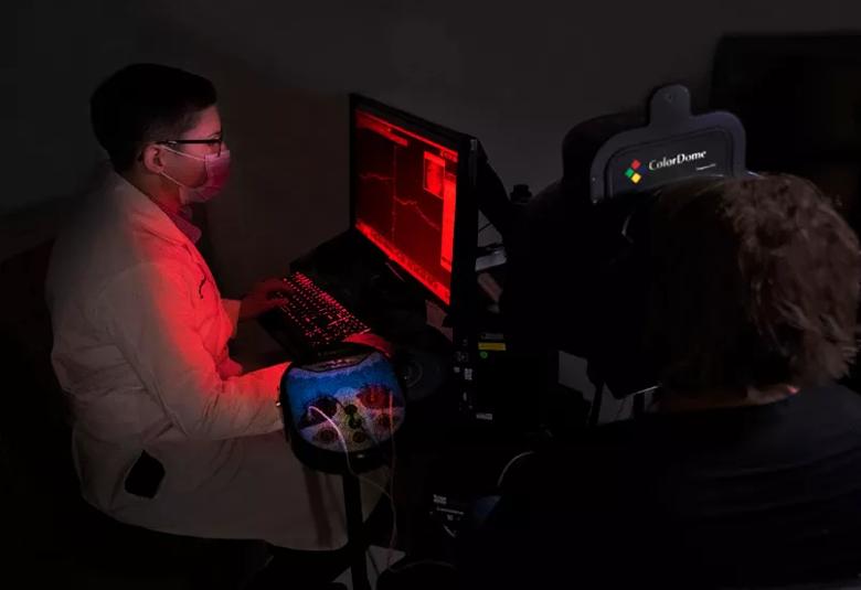 A doctor sits in the dark, in the red glow of a computer monitor