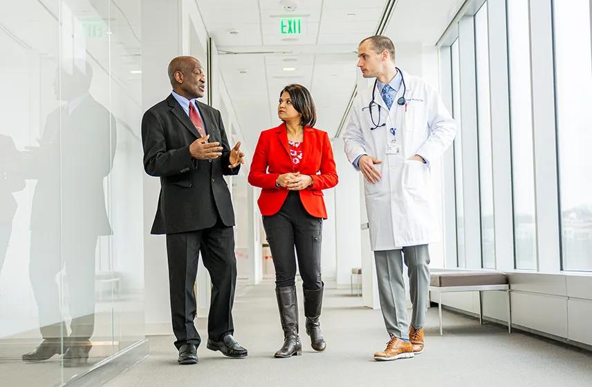 Hospital leaders walking together through a bright healthcare facility corridor.