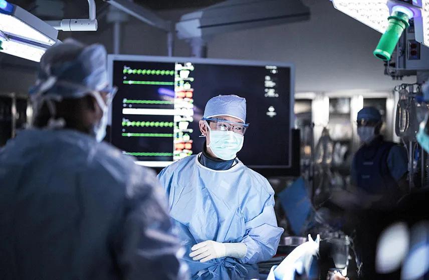 Surgical team collaborates in an operating room with patient monitors visible during a procedure.