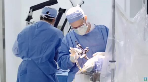 Surgeons performing a cerebrospinal procedure in an operating room.