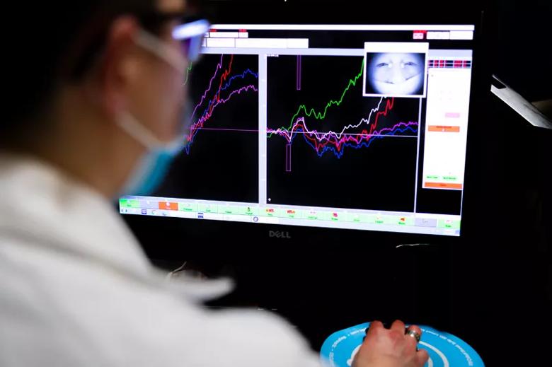 A doctor looks at a computer screen with different colored zig-zag lines.
