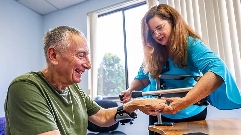 older man doing arm rehabilitation therapy with a healthcare provider